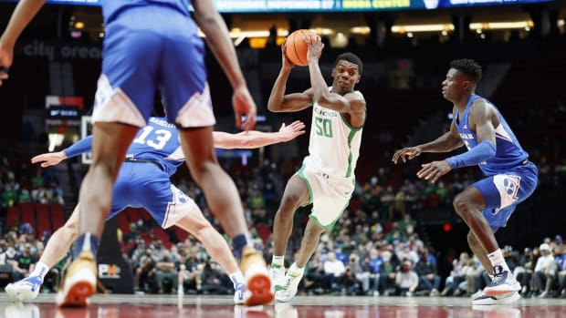 Nov 16, 2021; Portland, Oregon, USA; Oregon Ducks forward Eric Williams Jr. (50) drives for the basket between BYU Cougar guard Alex Barcello (13, left) and forward Gideon George (5, right) during the second half at Moda Center. Mandatory Credit: Soobum Im-USA TODAY Sports